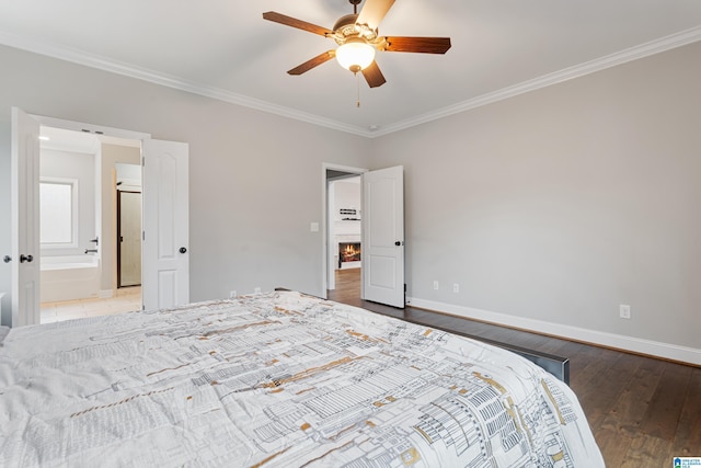 bedroom with a ceiling fan, a warm lit fireplace, wood finished floors, crown molding, and baseboards