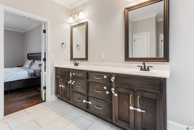 ensuite bathroom with double vanity, connected bathroom, crown molding, and a sink