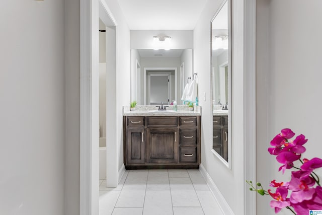 bathroom with tile patterned floors, baseboards, a tub to relax in, and vanity