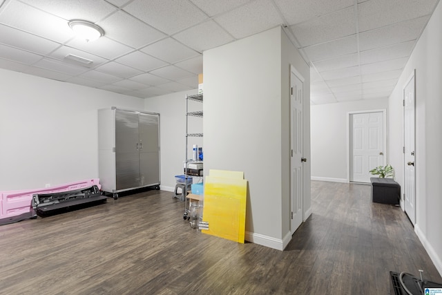 interior space featuring a drop ceiling, baseboards, and wood finished floors