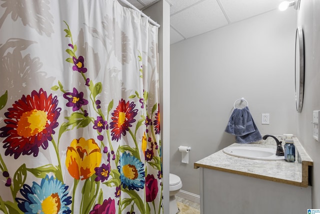 bathroom with toilet, a drop ceiling, curtained shower, baseboards, and vanity