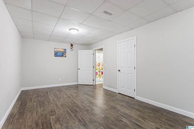 empty room featuring visible vents, a drop ceiling, baseboards, and wood finished floors