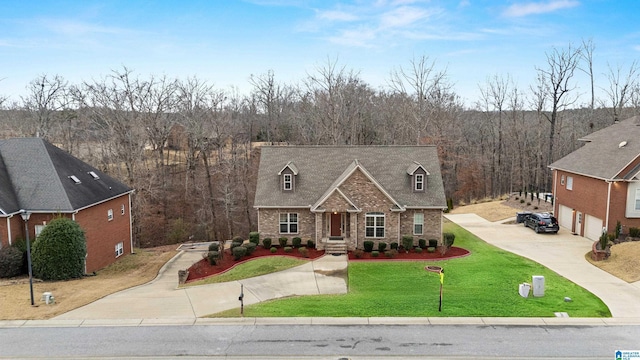 traditional home with concrete driveway, a front yard, a wooded view, a garage, and brick siding