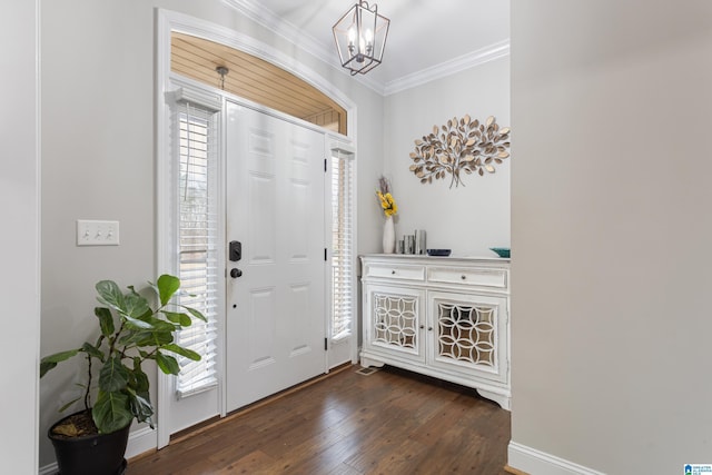 foyer with dark wood-style floors, crown molding, and an inviting chandelier