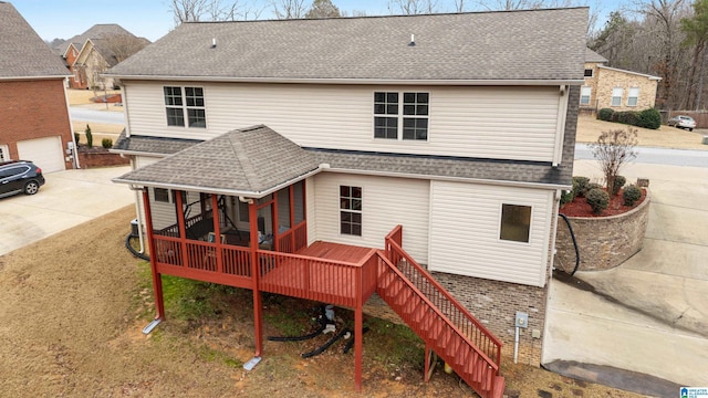 rear view of house with driveway, roof with shingles, stairs, and a sunroom