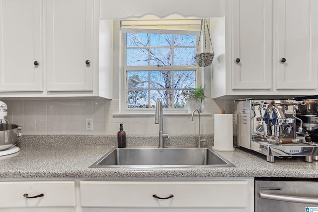 kitchen with white cabinets, tasteful backsplash, stainless steel dishwasher, and sink