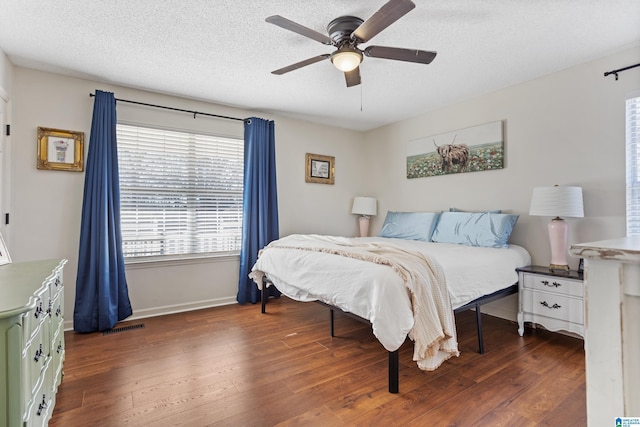 bedroom with a textured ceiling, ceiling fan, and dark wood-type flooring