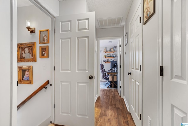 hall with a textured ceiling and dark wood-type flooring