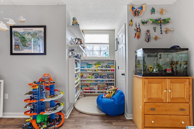 playroom with a textured ceiling and dark wood-type flooring