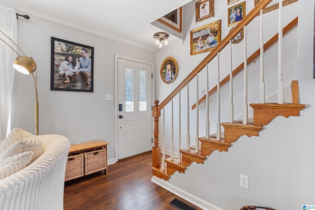 foyer entrance featuring a textured ceiling, dark hardwood / wood-style floors, and crown molding