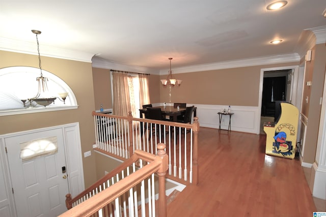 entryway featuring hardwood / wood-style floors, crown molding, and a notable chandelier