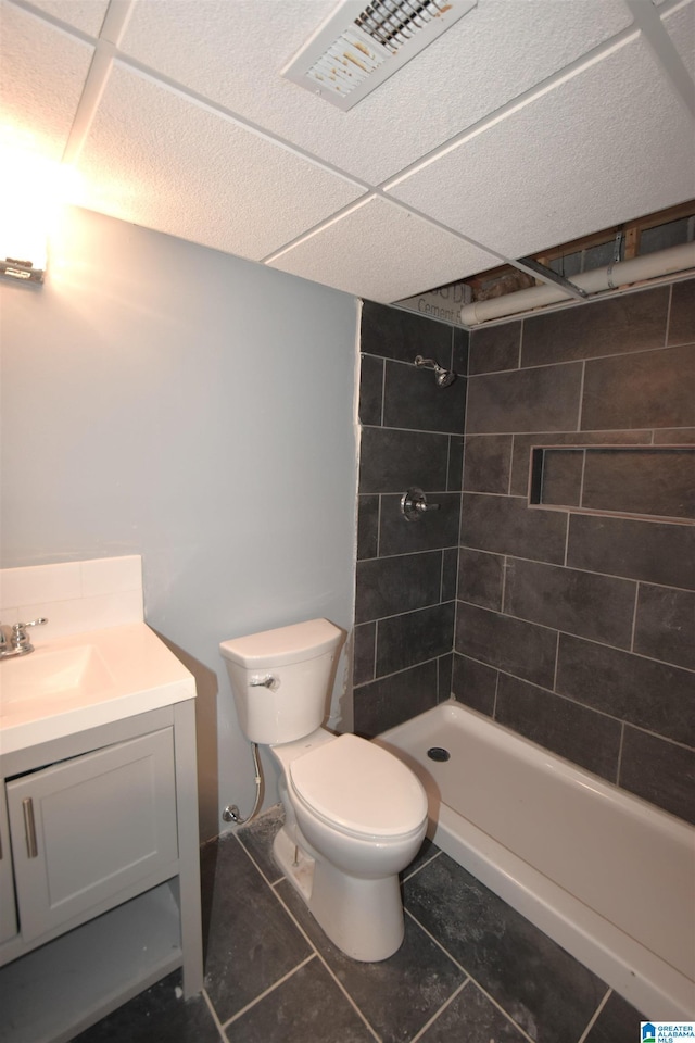 bathroom with tile patterned flooring, vanity, toilet, and a tile shower