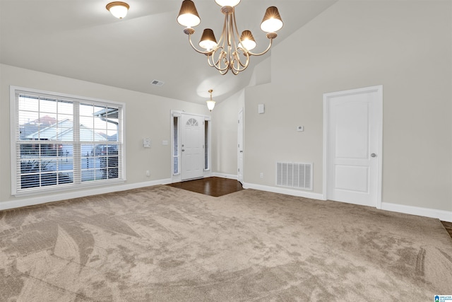 carpeted empty room featuring a notable chandelier and high vaulted ceiling