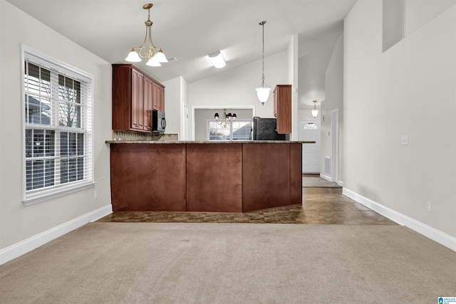 kitchen featuring a notable chandelier, decorative light fixtures, black fridge, and kitchen peninsula