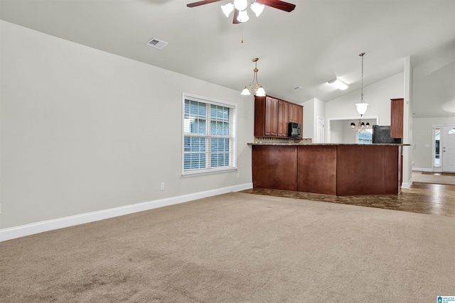 kitchen featuring dark carpet, ceiling fan with notable chandelier, hanging light fixtures, fridge, and kitchen peninsula