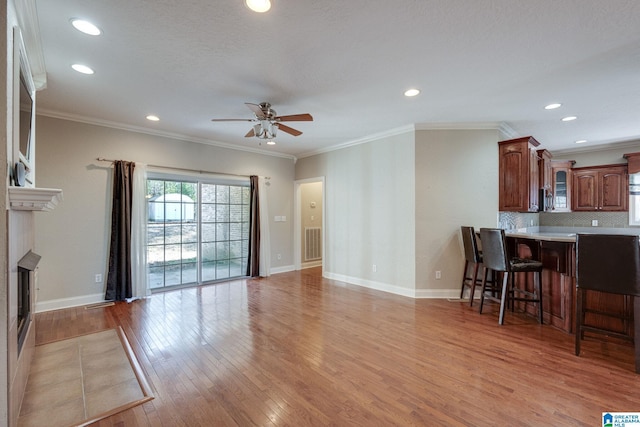 living room with light hardwood / wood-style flooring, ceiling fan, and ornamental molding