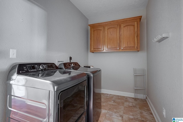 laundry area featuring cabinets, a textured ceiling, and separate washer and dryer