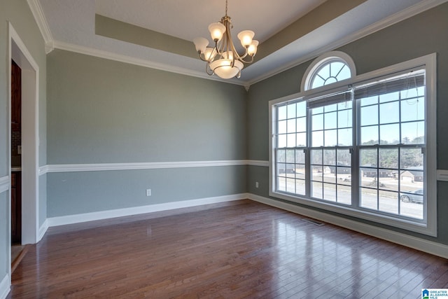 spare room featuring a tray ceiling, crown molding, dark hardwood / wood-style floors, and an inviting chandelier