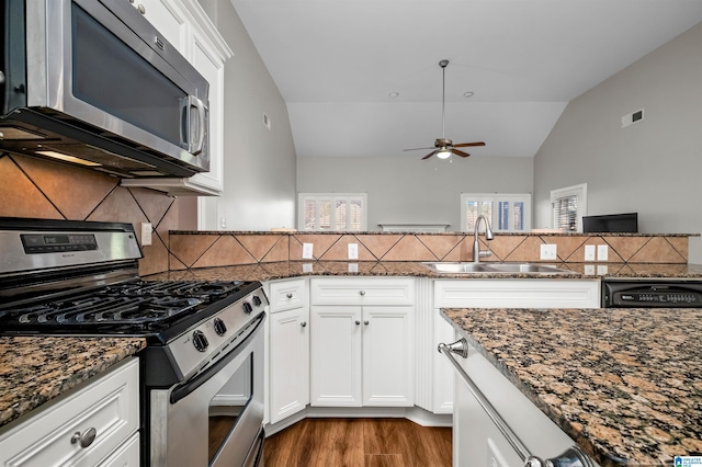 kitchen with white cabinets, appliances with stainless steel finishes, dark stone counters, and sink