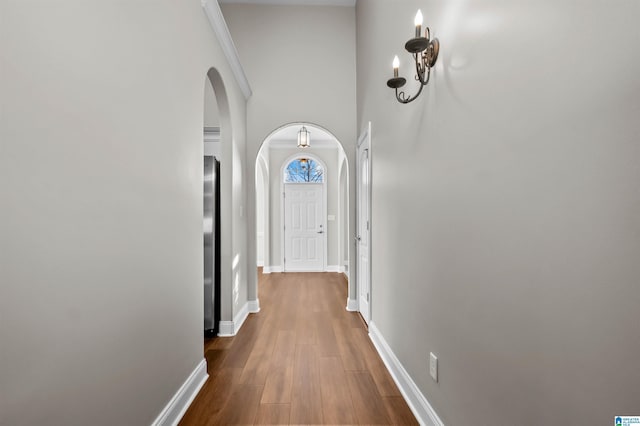 corridor featuring wood-type flooring and a high ceiling