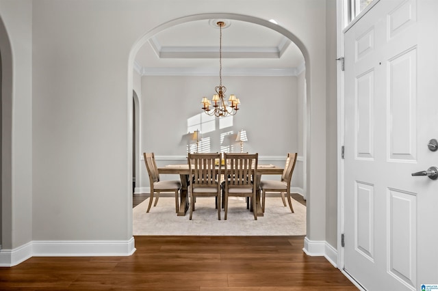 dining room with ornamental molding, dark hardwood / wood-style flooring, a raised ceiling, and a notable chandelier