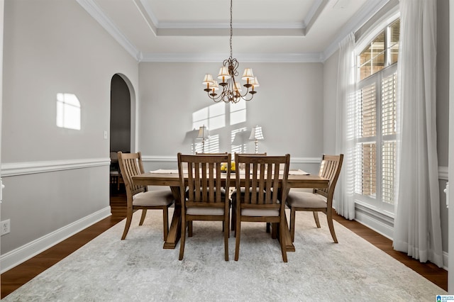 dining area with hardwood / wood-style floors, a notable chandelier, and a tray ceiling