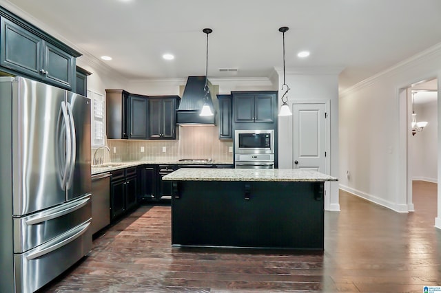 kitchen with light stone countertops, custom exhaust hood, pendant lighting, a center island, and appliances with stainless steel finishes