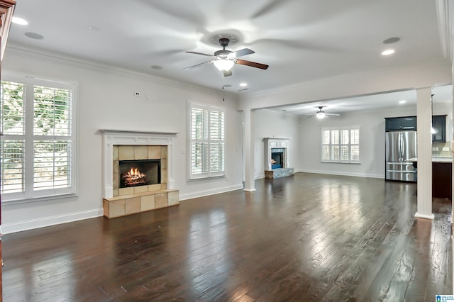 unfurnished living room featuring a fireplace, ornamental molding, ceiling fan, and dark hardwood / wood-style floors