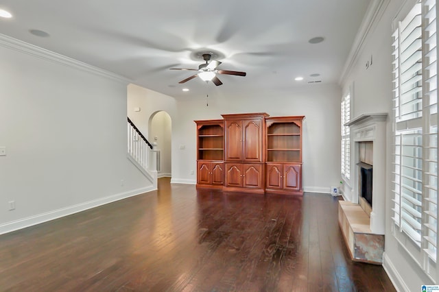 unfurnished living room featuring ceiling fan, crown molding, and dark wood-type flooring