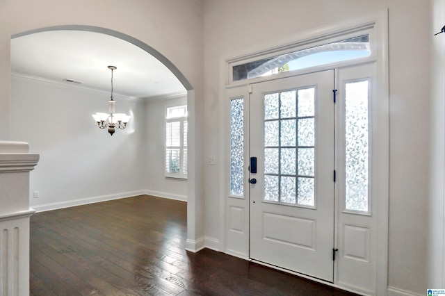 foyer entrance with a notable chandelier, ornamental molding, and a wealth of natural light