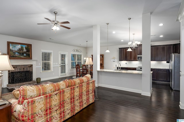 living room with dark hardwood / wood-style flooring, ceiling fan with notable chandelier, and sink