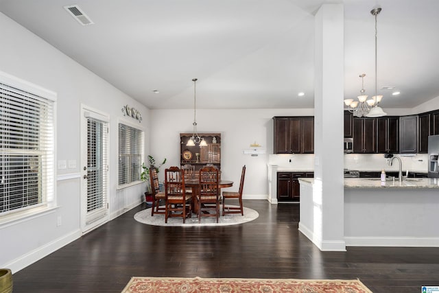 dining area featuring vaulted ceiling, sink, dark wood-type flooring, and a chandelier