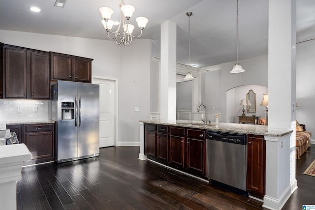 kitchen featuring appliances with stainless steel finishes, light stone counters, sink, decorative light fixtures, and a chandelier