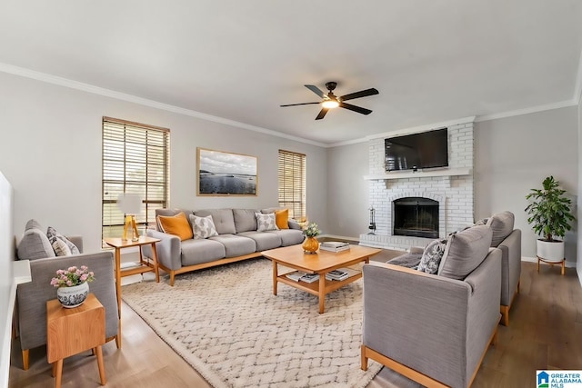 living room with ceiling fan, wood-type flooring, ornamental molding, and a brick fireplace