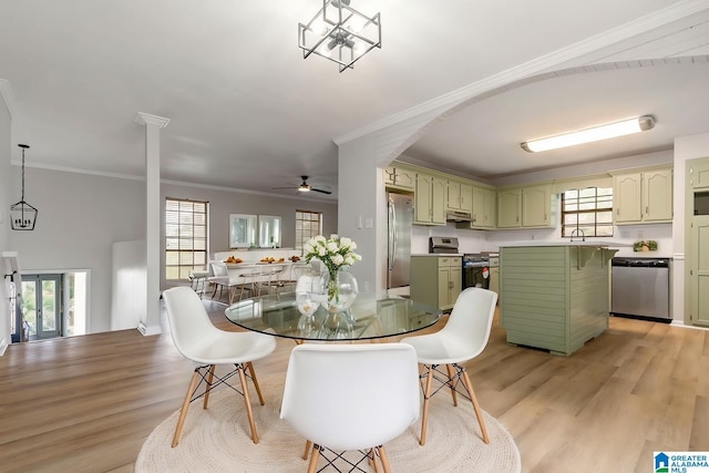 dining area with ceiling fan with notable chandelier, ornamental molding, a wealth of natural light, and light hardwood / wood-style flooring