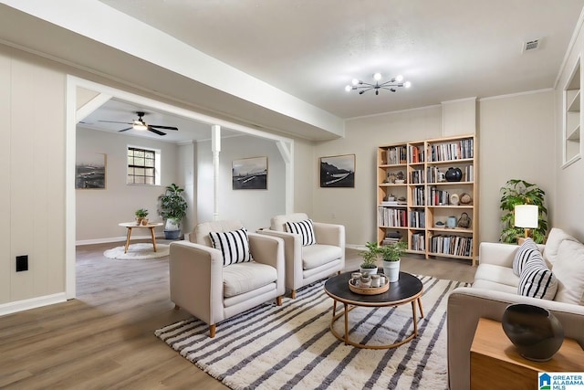 living area featuring ceiling fan with notable chandelier, hardwood / wood-style flooring, and crown molding