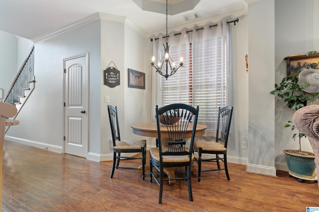 dining room with dark hardwood / wood-style floors, ornamental molding, a tray ceiling, and a chandelier