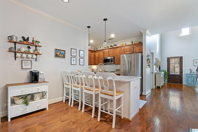 kitchen with a kitchen breakfast bar, dark hardwood / wood-style flooring, light stone counters, stainless steel appliances, and pendant lighting