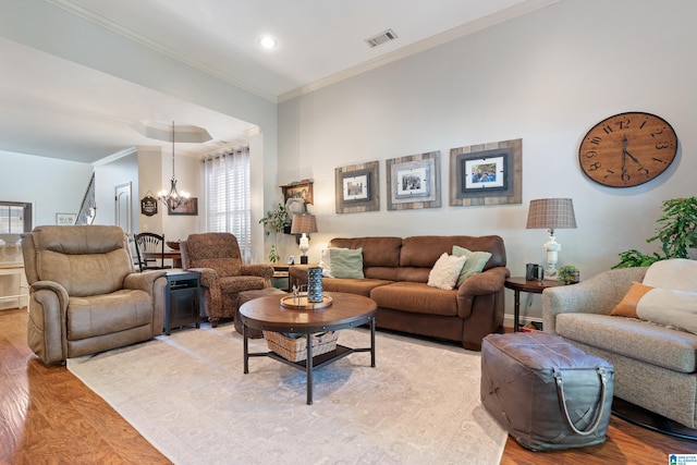 living room with light hardwood / wood-style floors, an inviting chandelier, and ornamental molding