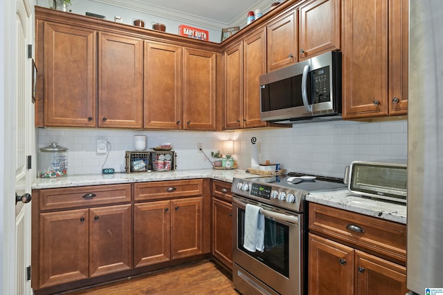 kitchen with light stone countertops, stainless steel appliances, dark hardwood / wood-style flooring, backsplash, and crown molding