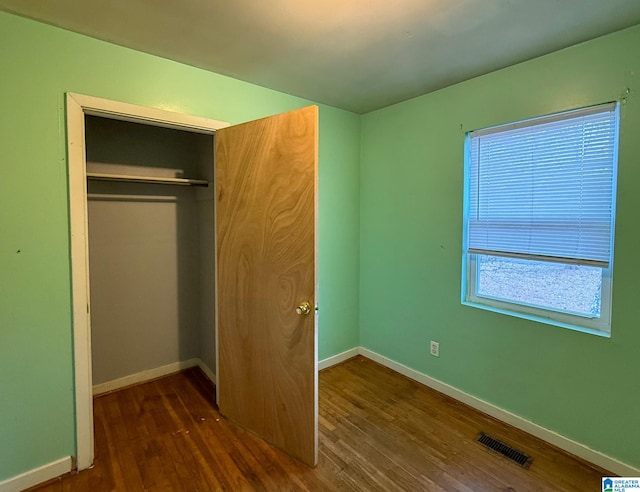 unfurnished bedroom with a closet and dark hardwood / wood-style floors