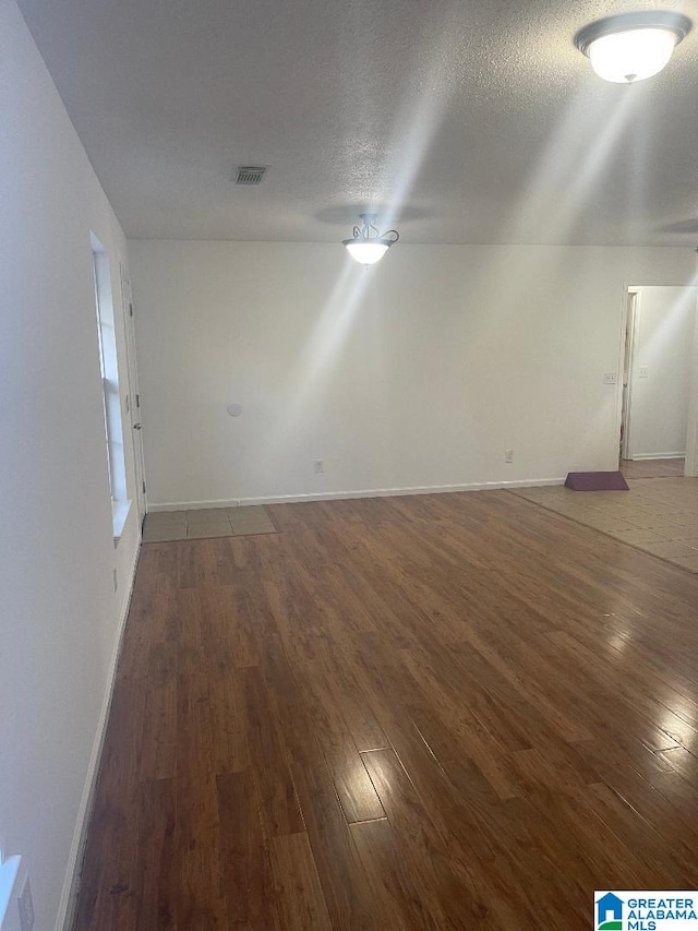 empty room featuring a textured ceiling and dark wood-type flooring