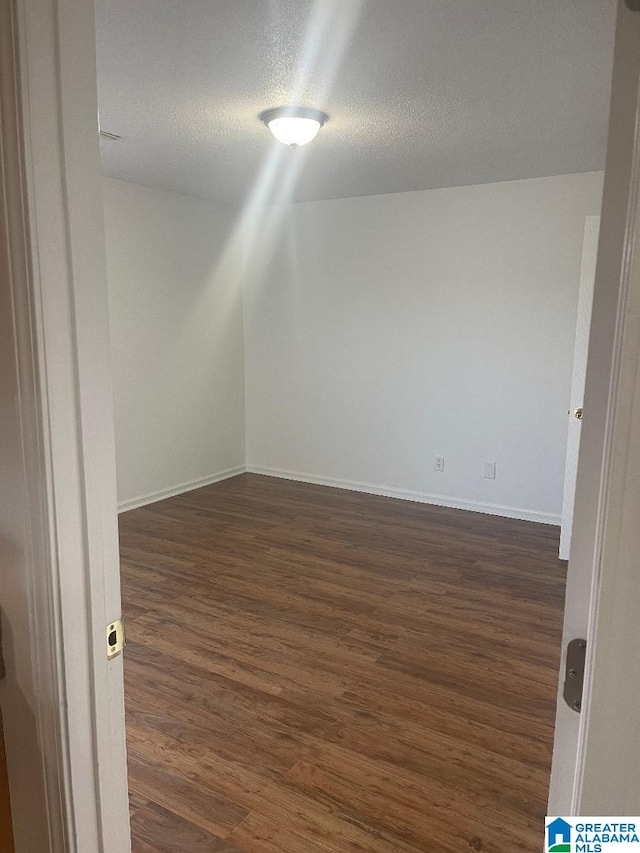 empty room with dark hardwood / wood-style flooring and a textured ceiling