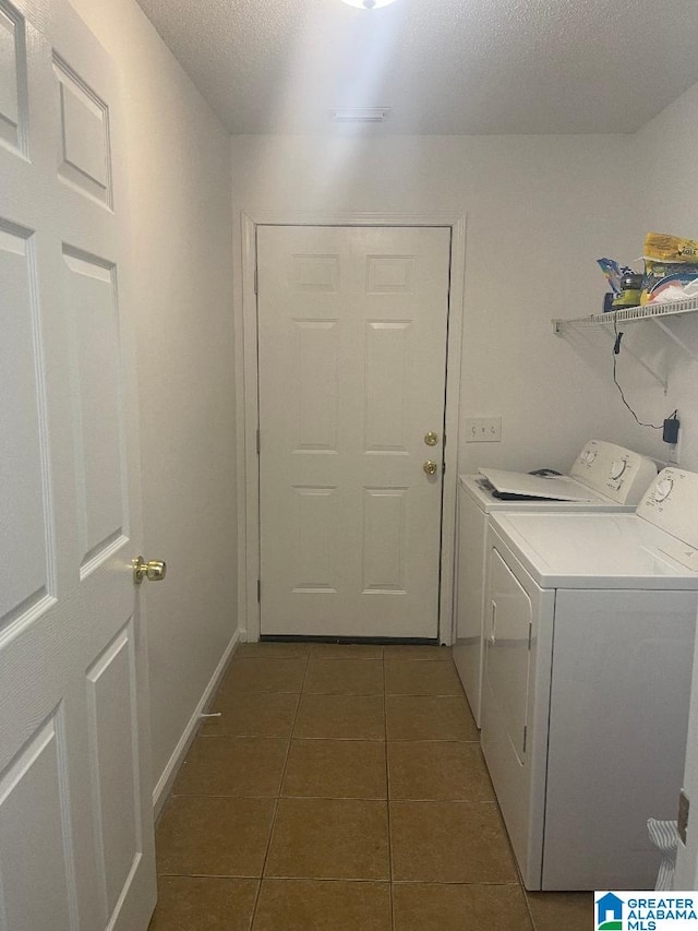 washroom featuring washing machine and dryer, dark tile patterned floors, and a textured ceiling