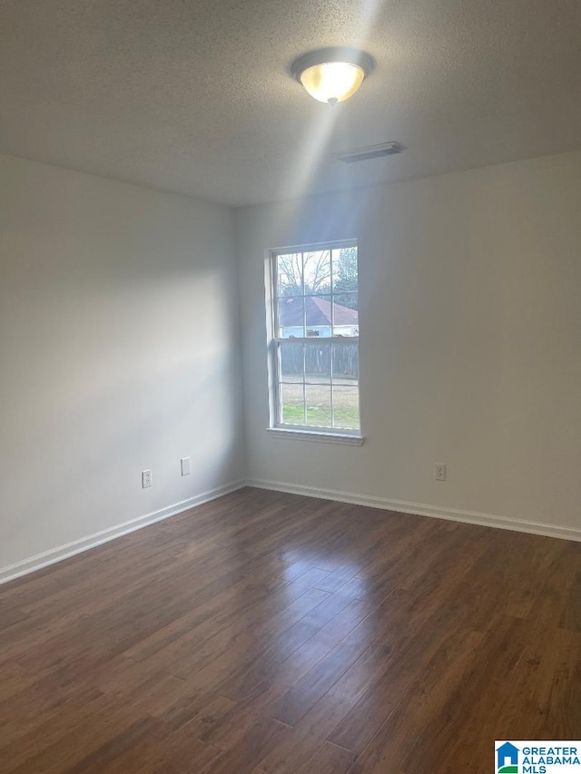 unfurnished room featuring a textured ceiling and dark hardwood / wood-style floors