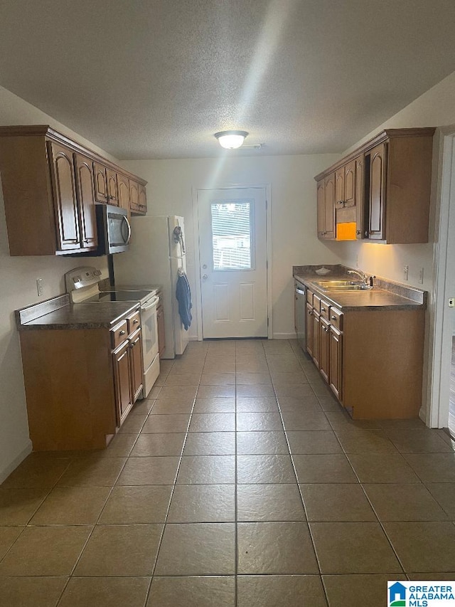 kitchen featuring sink, tile patterned flooring, a textured ceiling, and appliances with stainless steel finishes