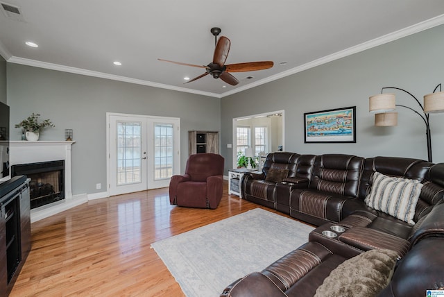 living room featuring ceiling fan, light wood-type flooring, crown molding, and french doors