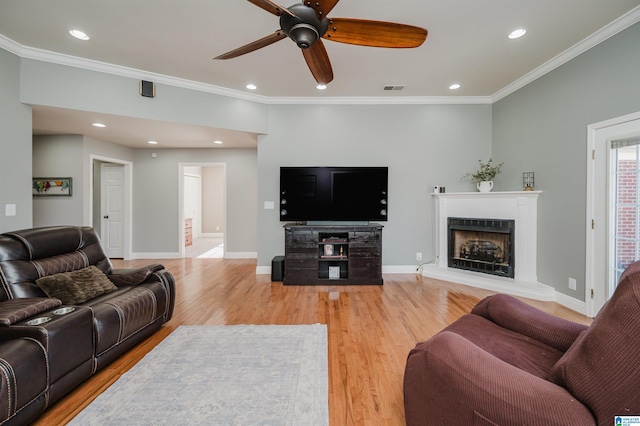 living room featuring crown molding, ceiling fan, and light wood-type flooring