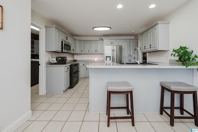 kitchen with gray cabinetry, sink, a kitchen bar, and stainless steel appliances