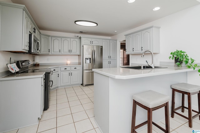 kitchen with a kitchen breakfast bar, stainless steel appliances, light tile patterned floors, and sink